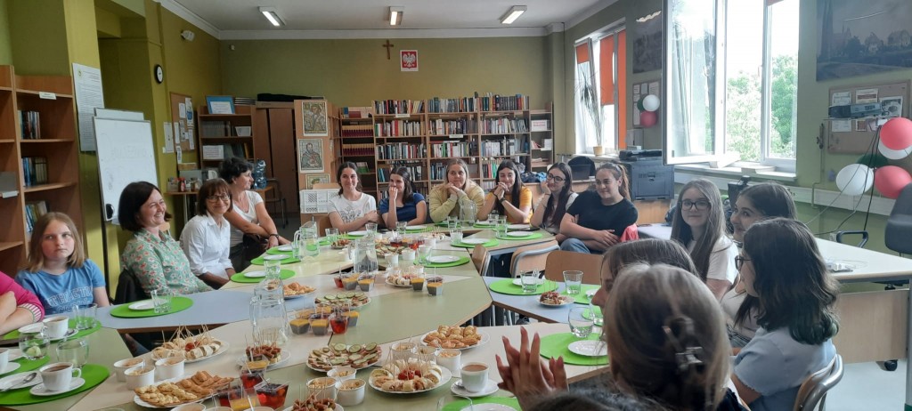 Uczniowie polscy i ich rodzice, włoskie uczennice siedząc wokół stołu słuchają Pani Dyrektor